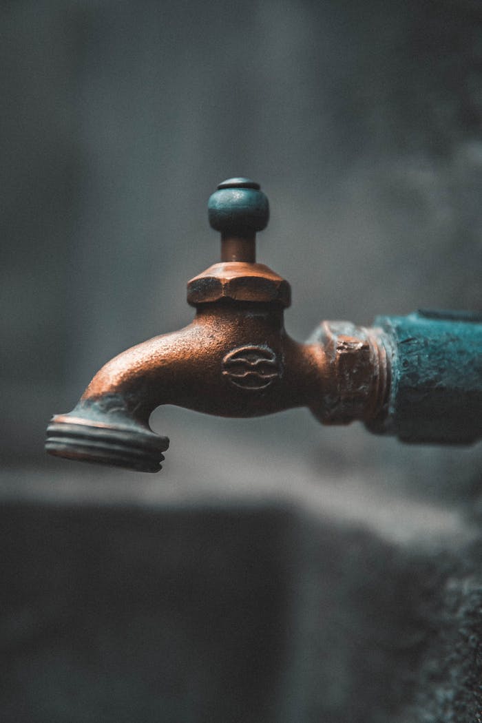 Detailed close-up of a rustic metal faucet outdoors with soft focus background.